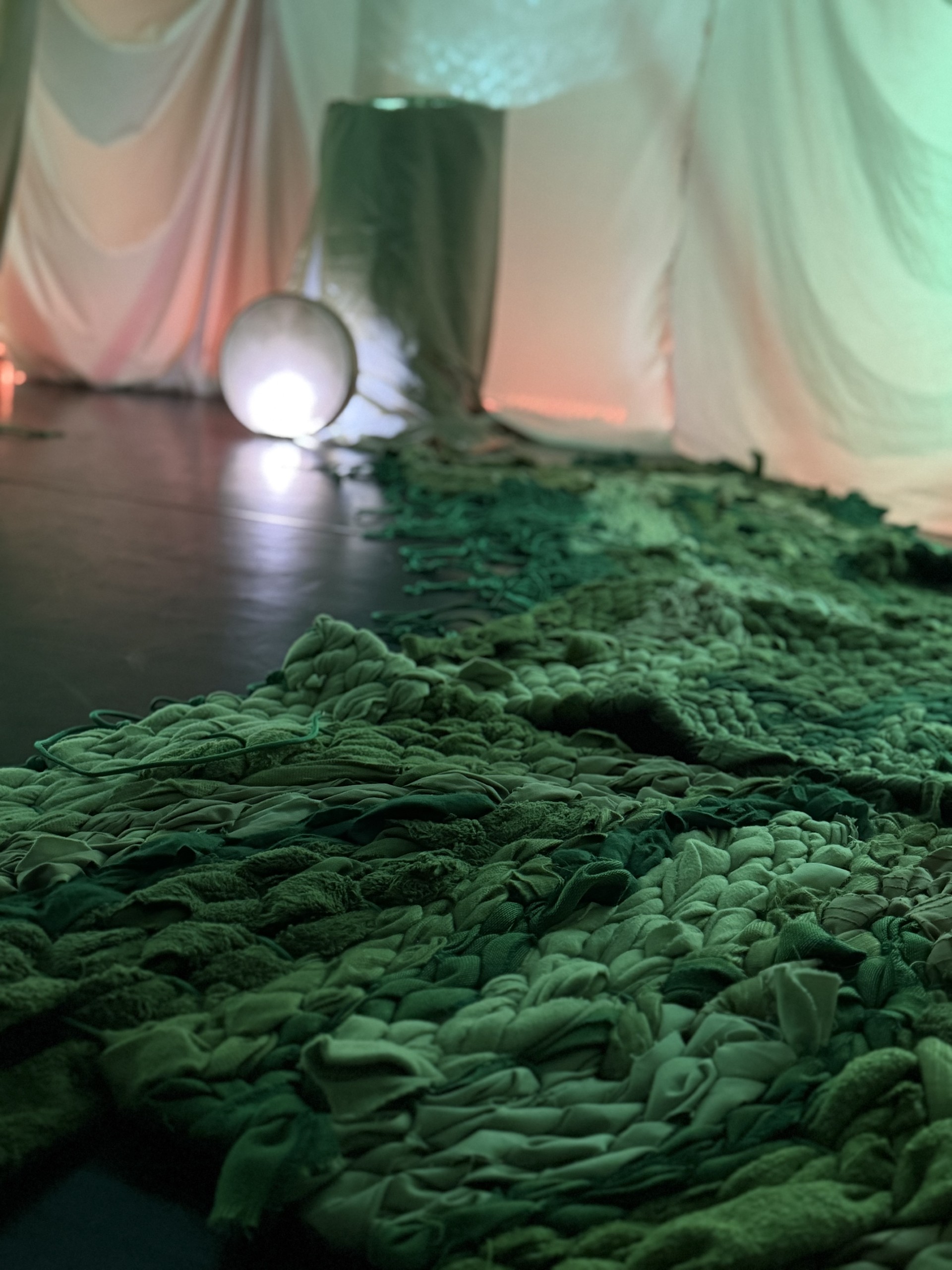 Photo de l'intérieur du dôme du micro-spectacle "Yggradsil". On voit des tapis tissés main de couleur vert et découvre l'ambiance cosy spectacle.